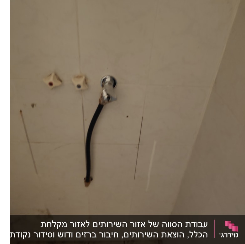 ברז מים עם צינור שחור על קיר לבן